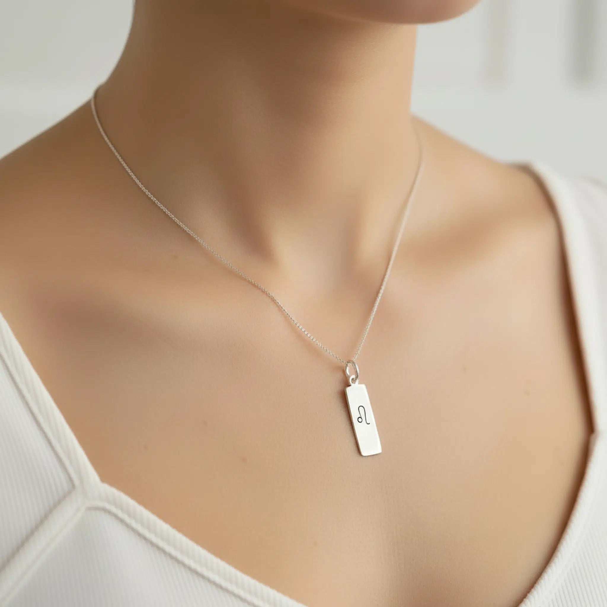 Sterling Silver necklace with a rectangular pendant with a leo zodiac symbol on a womans neckl