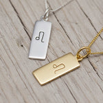 leo zodiac necklaces in sterling silver and gold plated sterling silver on a wooden surface