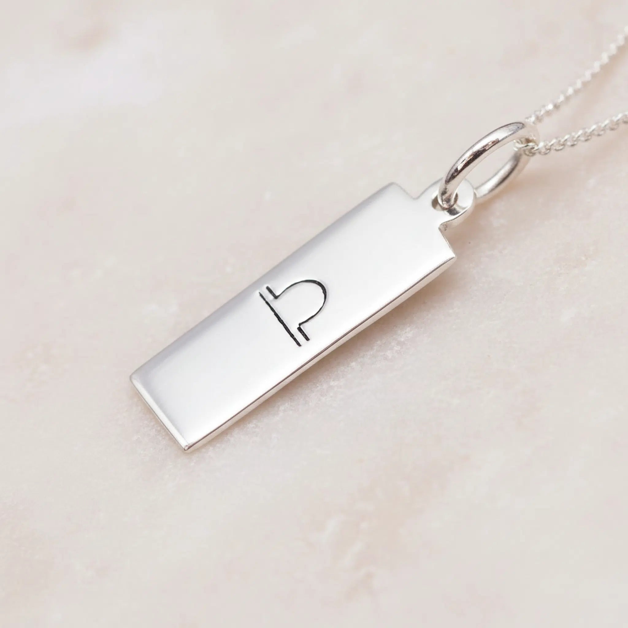 sterling Silver necklace with a rectangular pendant featuring an engraved libra zodiac symbol on a light pink background.