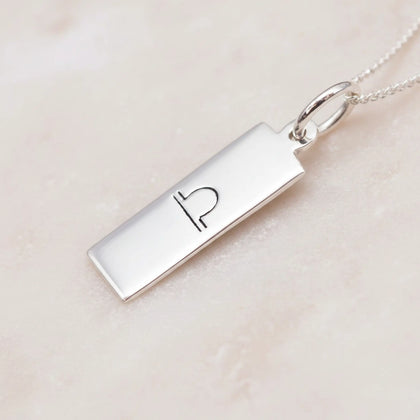 sterling Silver necklace with a rectangular pendant featuring an engraved libra zodiac symbol on a light pink background.