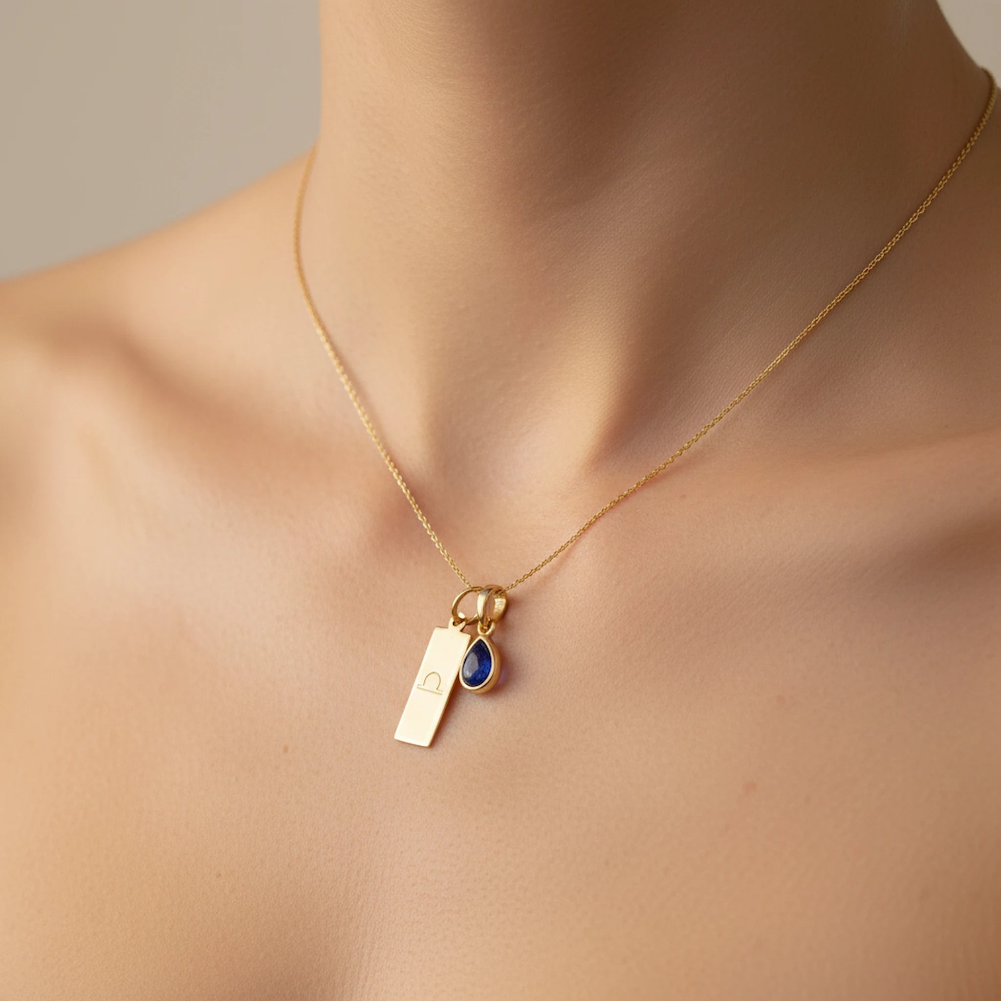 Gold Libra Zodiac necklace with a September birthstone natural sapphire gemstone pendant being worn