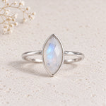 sterling silver rose-cut bezel-set marquise shaped natural moonstone ring on a light stone surface