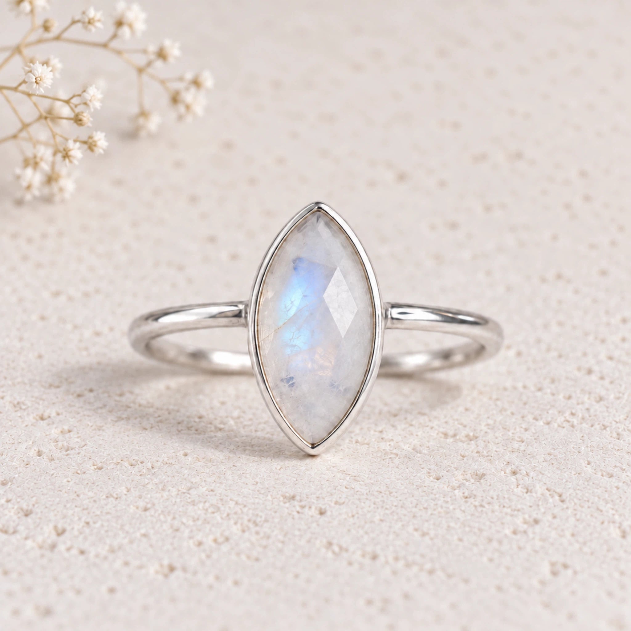 sterling silver rose-cut bezel-set marquise shaped natural moonstone ring on a light stone surface