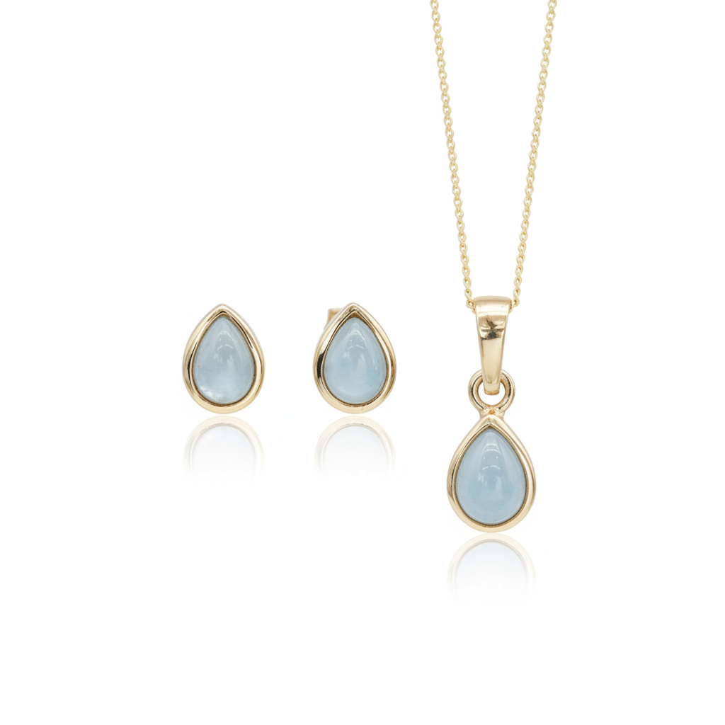 Gold jewelry set featuring a teardrop pendant necklace and matching stud earrings, each with a light blue teardrop gemstone in a gold bezel setting, shown on a white background with soft reflections.