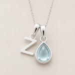 Sterling Silver double pendant necklace with a teardrop-shaped march birthstone aquamarine gemstone pendant and a Z letter pendant on a beige background