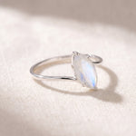 Marquise rainbow moonstone ring at a 45 degree angle on linen, showing the prongs and wrap band