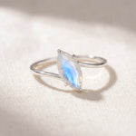 Marquise rainbow moonstone ring flat lay on warm white linen, faceted moonstone on a silver wrap band