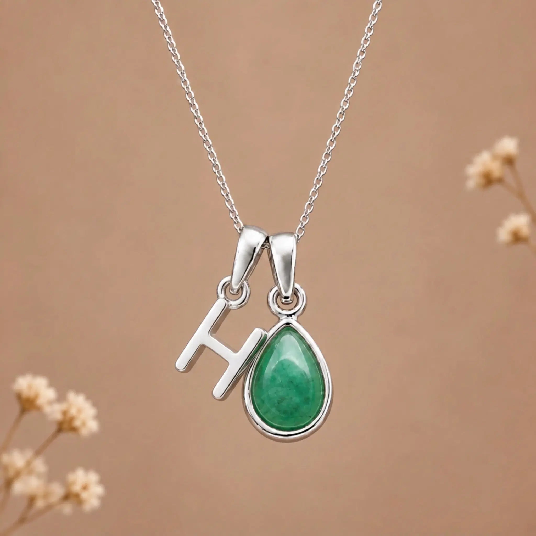 sterling silver initial h may birthstone natural emerald pendant necklace against a dark warm beige background