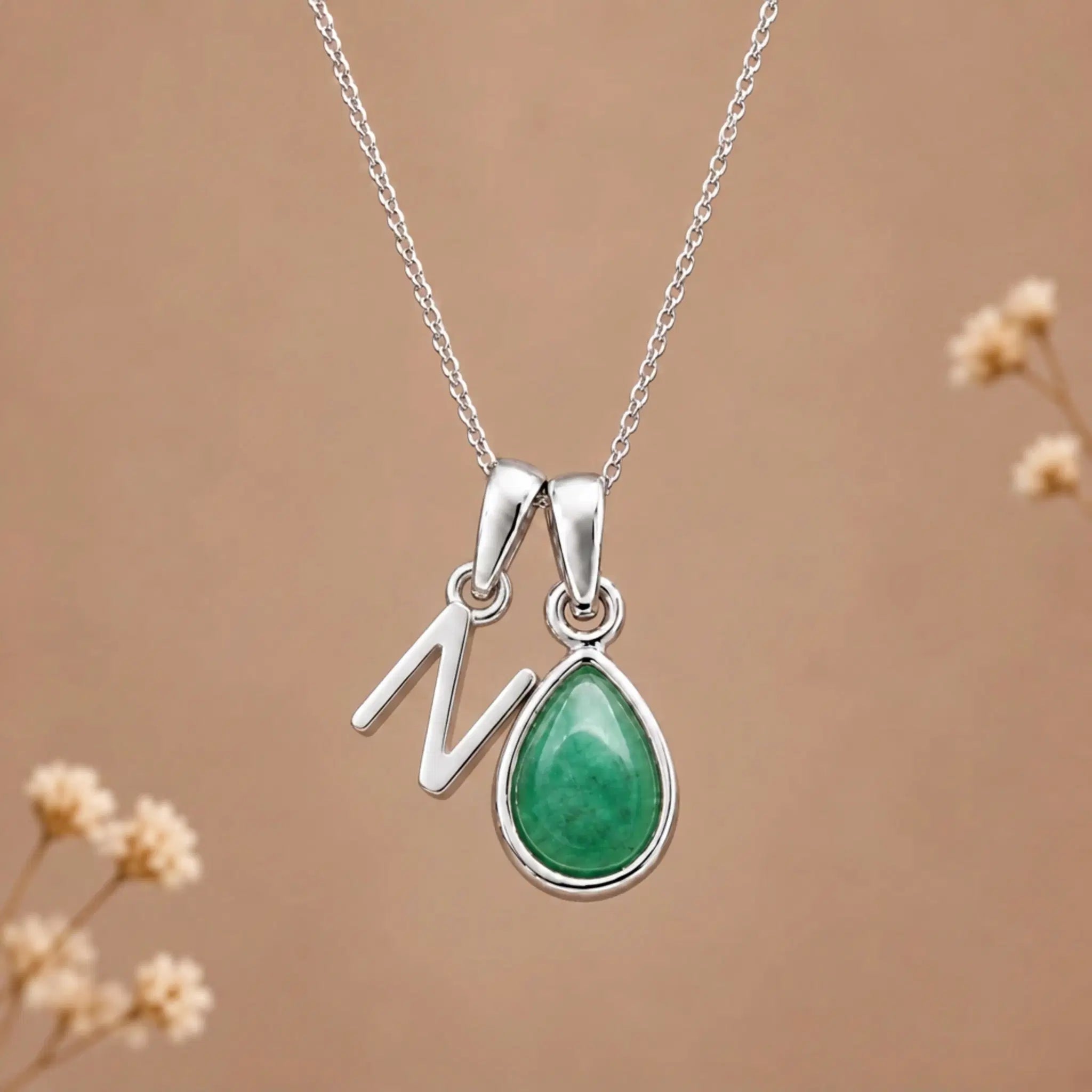 sterling silver initial n may birthstone natural emerald pendant necklace against a dark warm beige background