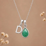 sterling silver initial d may birthstone natural emerald pendant necklace against a dark warm beige background