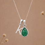 sterling silver initial k may birthstone natural emerald pendant necklace against a dark warm beige background