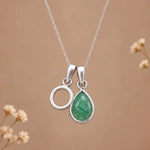 sterling silver initial o may birthstone natural emerald pendant necklace against a dark warm beige background