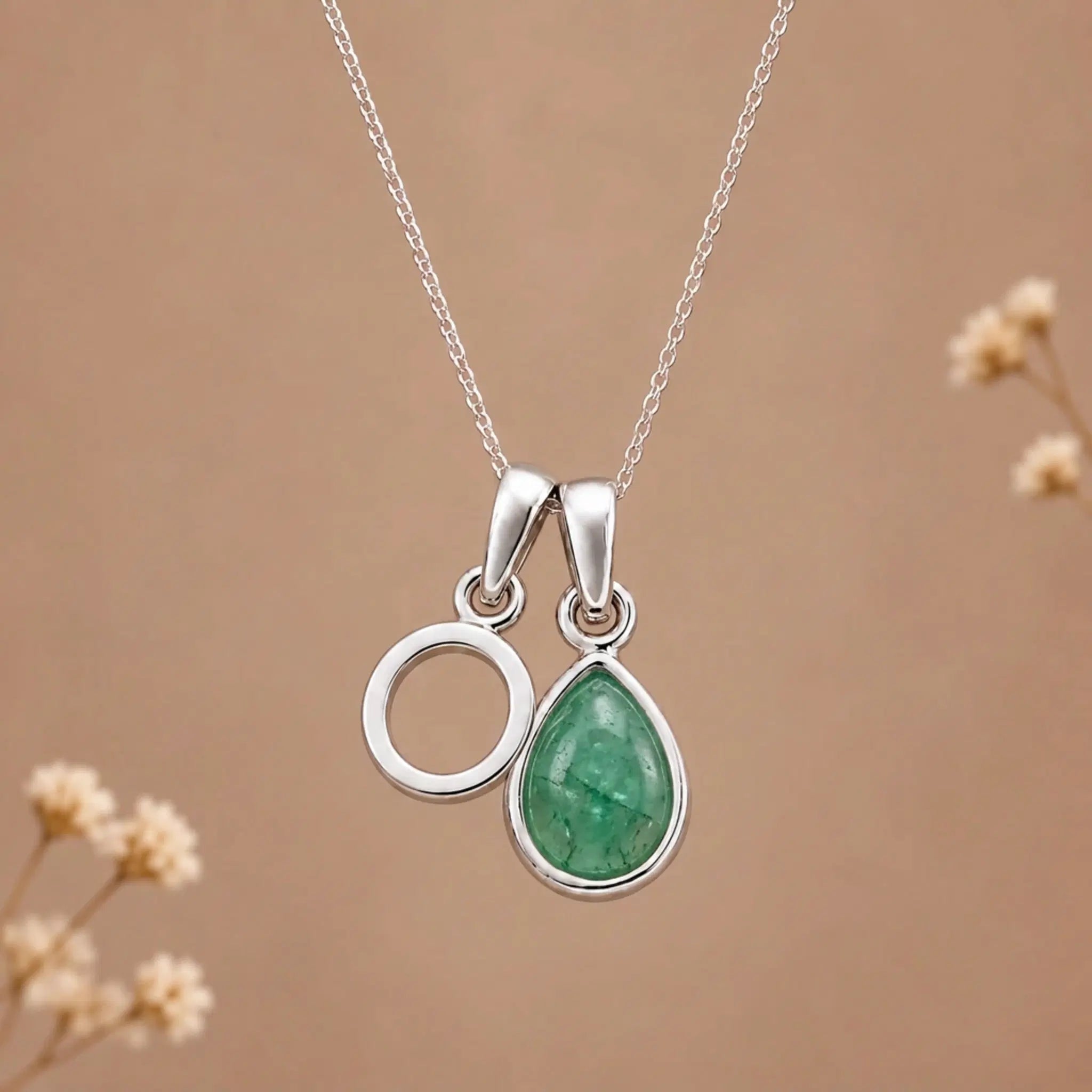 sterling silver initial o may birthstone natural emerald pendant necklace against a dark warm beige background
