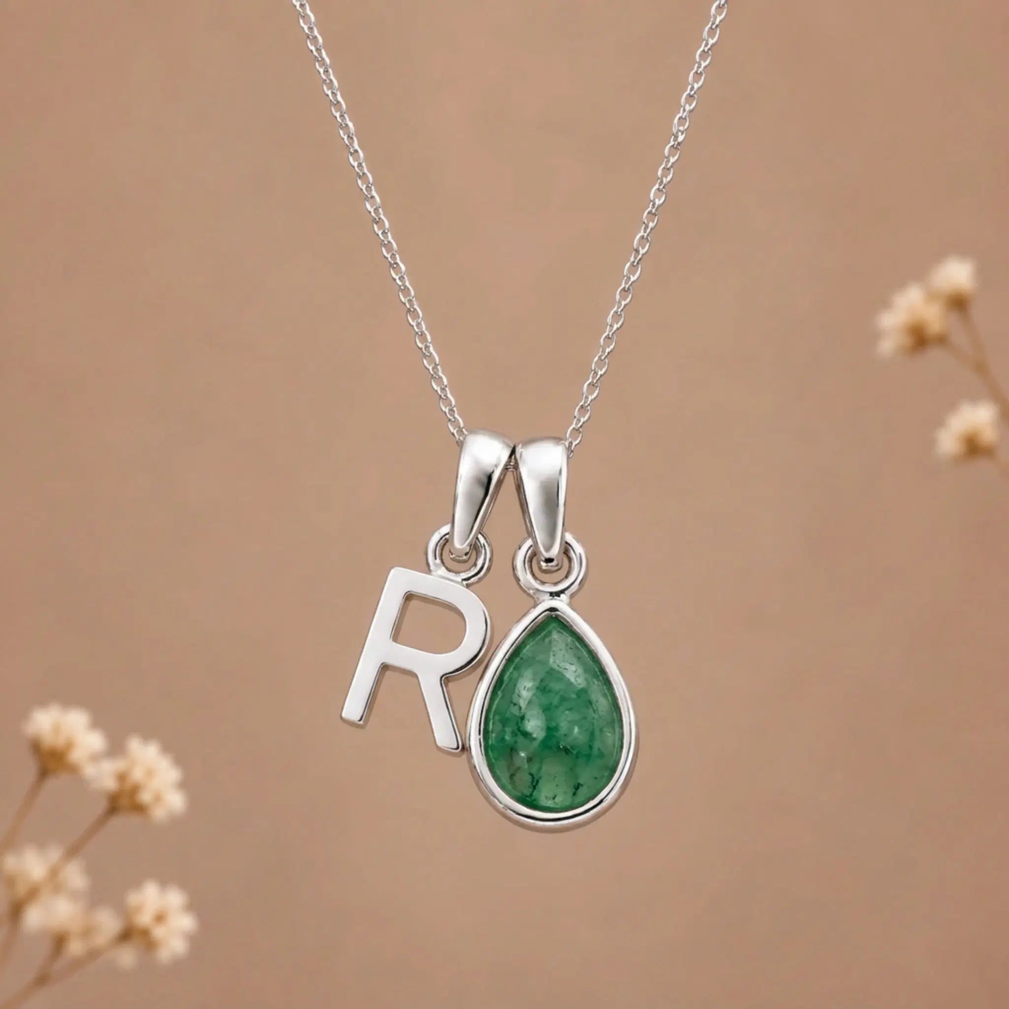 sterling silver initial r may birthstone natural emerald pendant necklace against a dark warm beige background