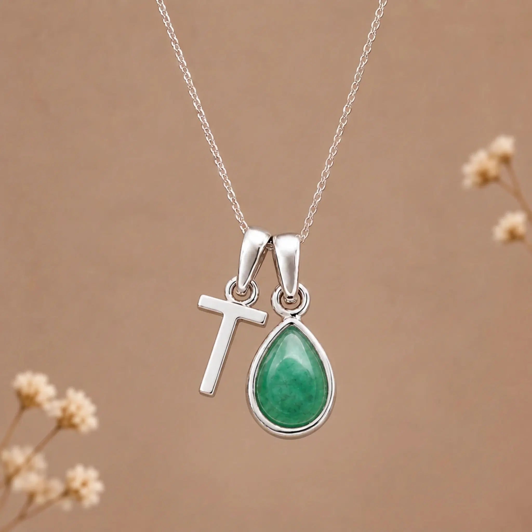 sterling silver initial t may birthstone natural emerald pendant necklace against a dark warm beige background
