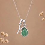 sterling silver initial y may birthstone natural emerald pendant necklace against a dark warm beige background