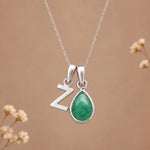 sterling silver initial z may birthstone natural emerald pendant necklace against a dark warm beige background