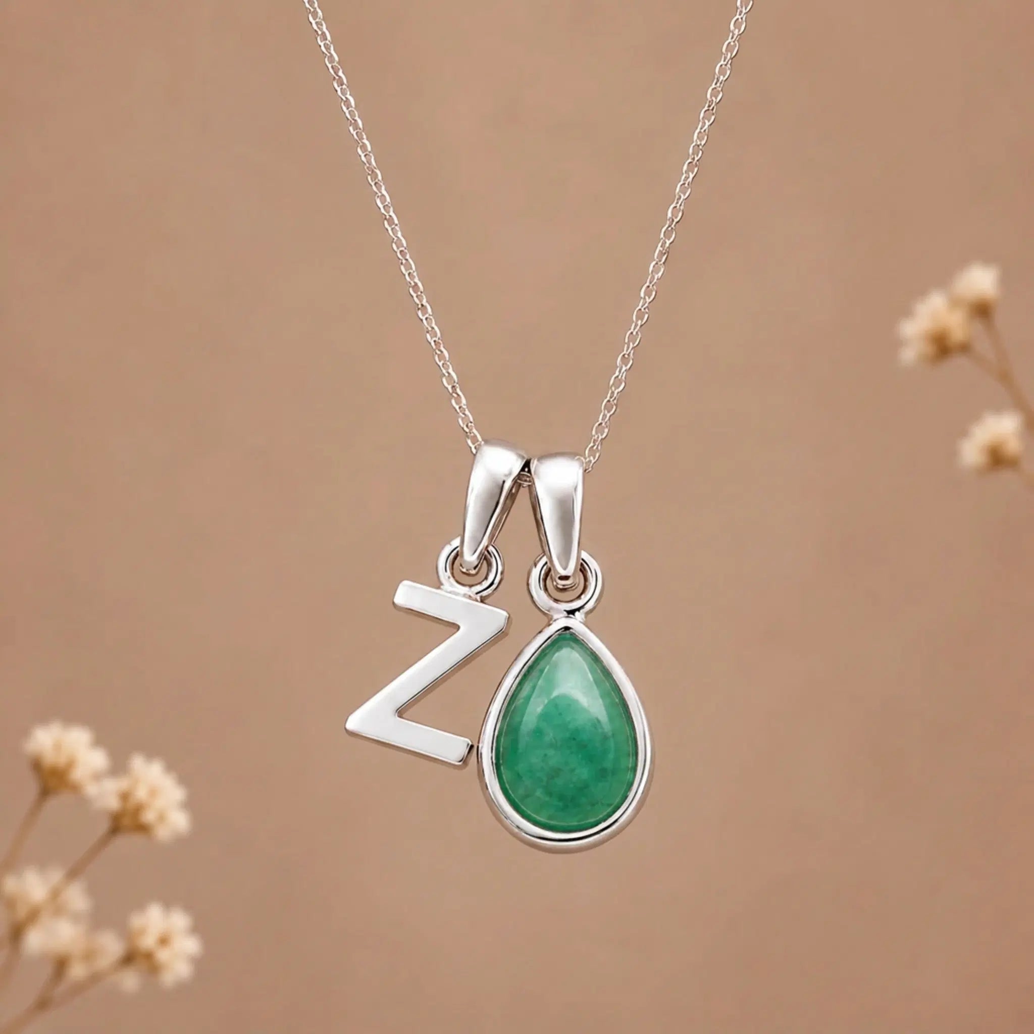 sterling silver initial z may birthstone natural emerald pendant necklace against a dark warm beige background