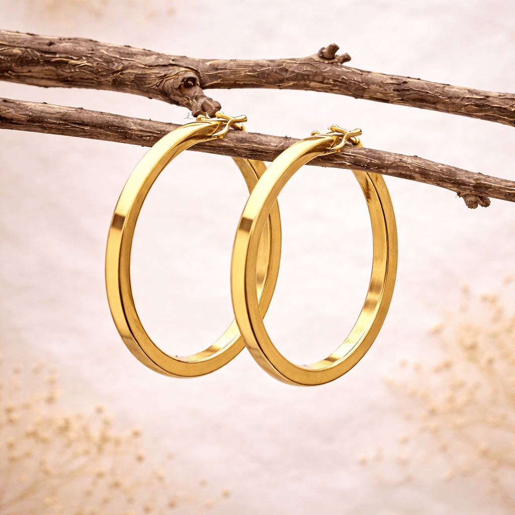 Gold hoop earrings hanging on a branch with a natural background