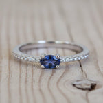 Ring with a blue gemstone and diamond accents on a textured surface