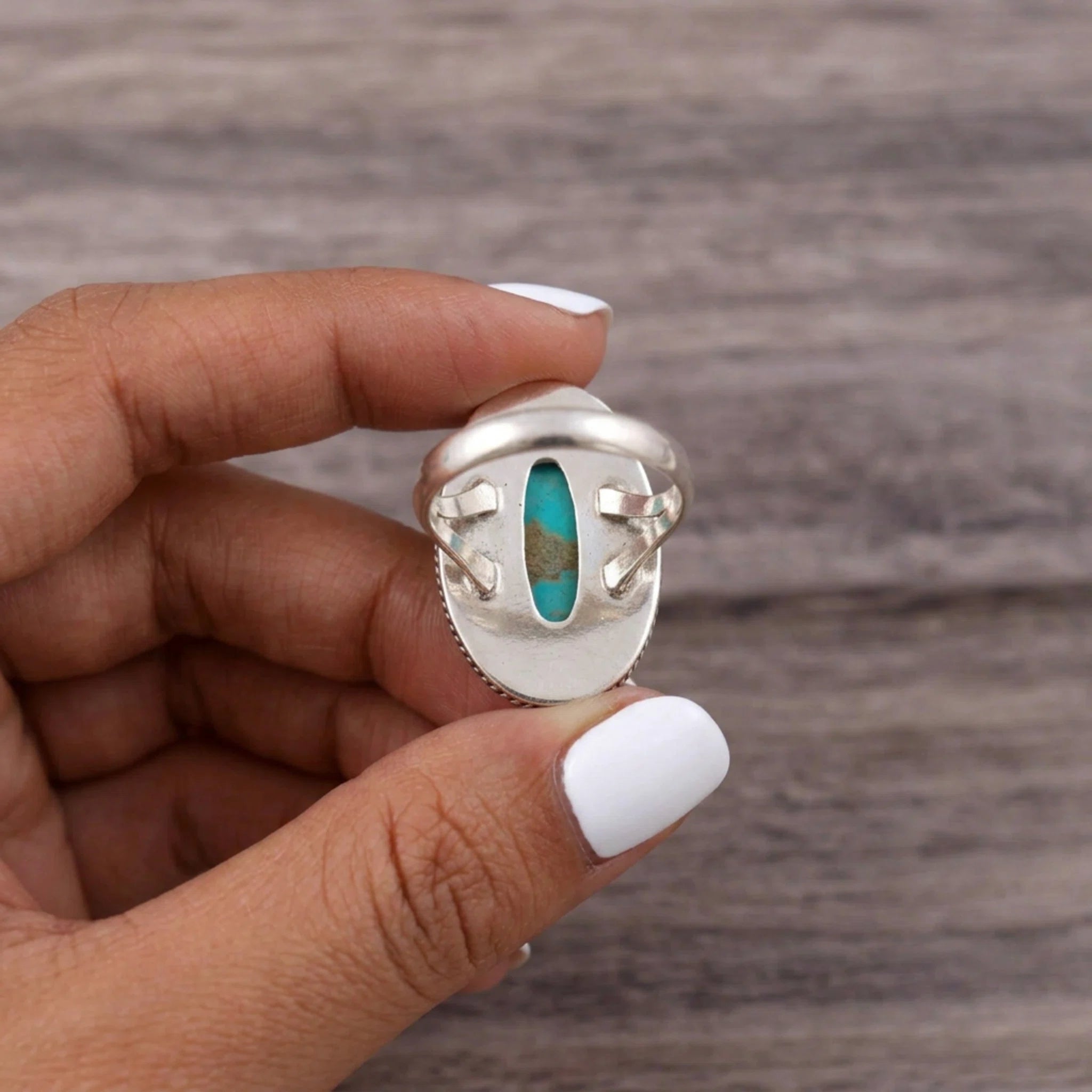 fingers holding a Sterling Silver Boho Ring with mohave turquoise gemstone showing the back of the open ring