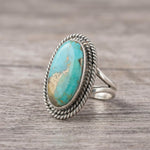 side view of a Sterling Silver Boho Ring with mohave turquoise gemstone on a wooden surface