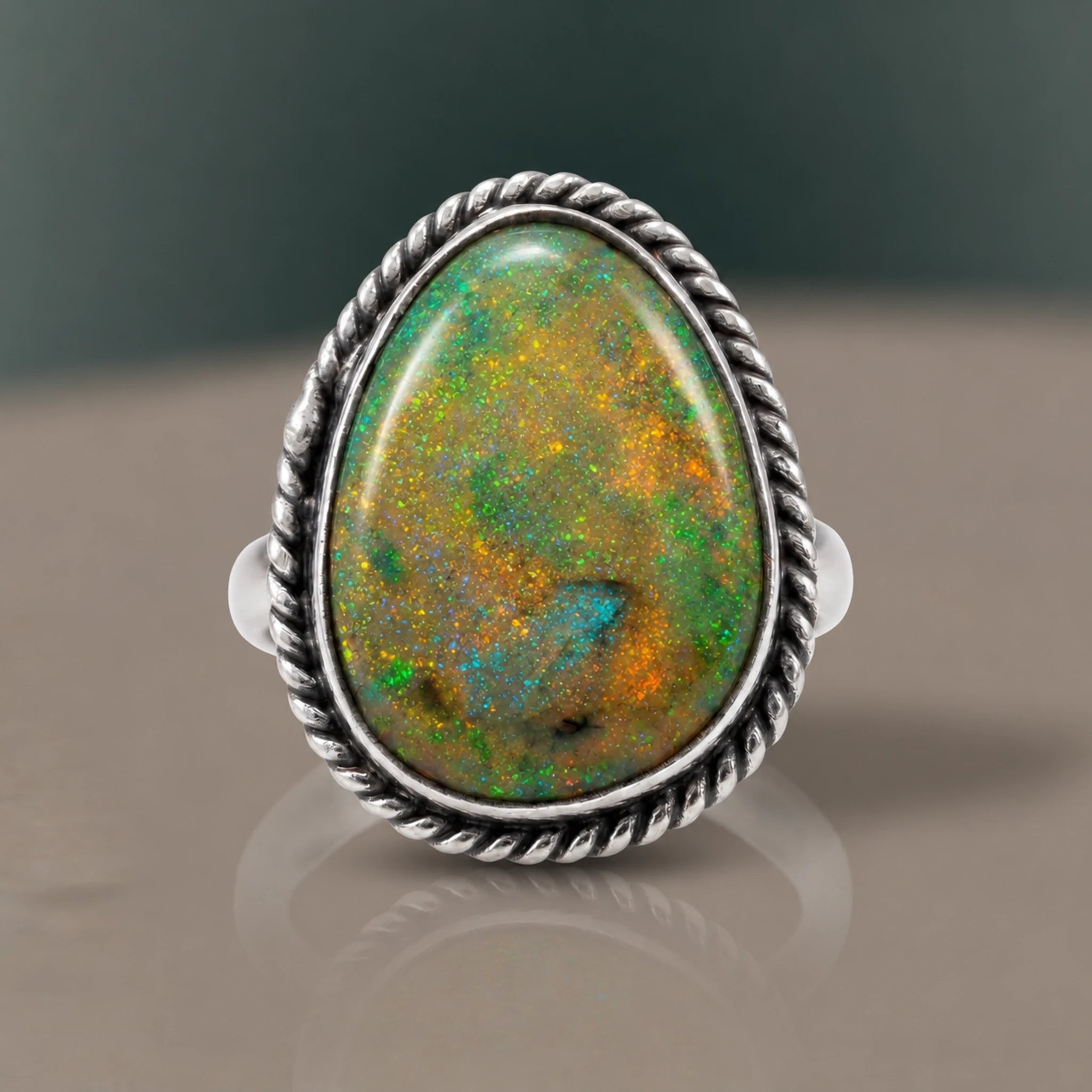 Monarch Opal Ring with a green opal and orange flashes of colour in a twisted rope bezel, close-up