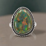 Monarch Opal Ring with an olive green opal and rainbow pinfire flashes in a twisted rope bezel, close-up