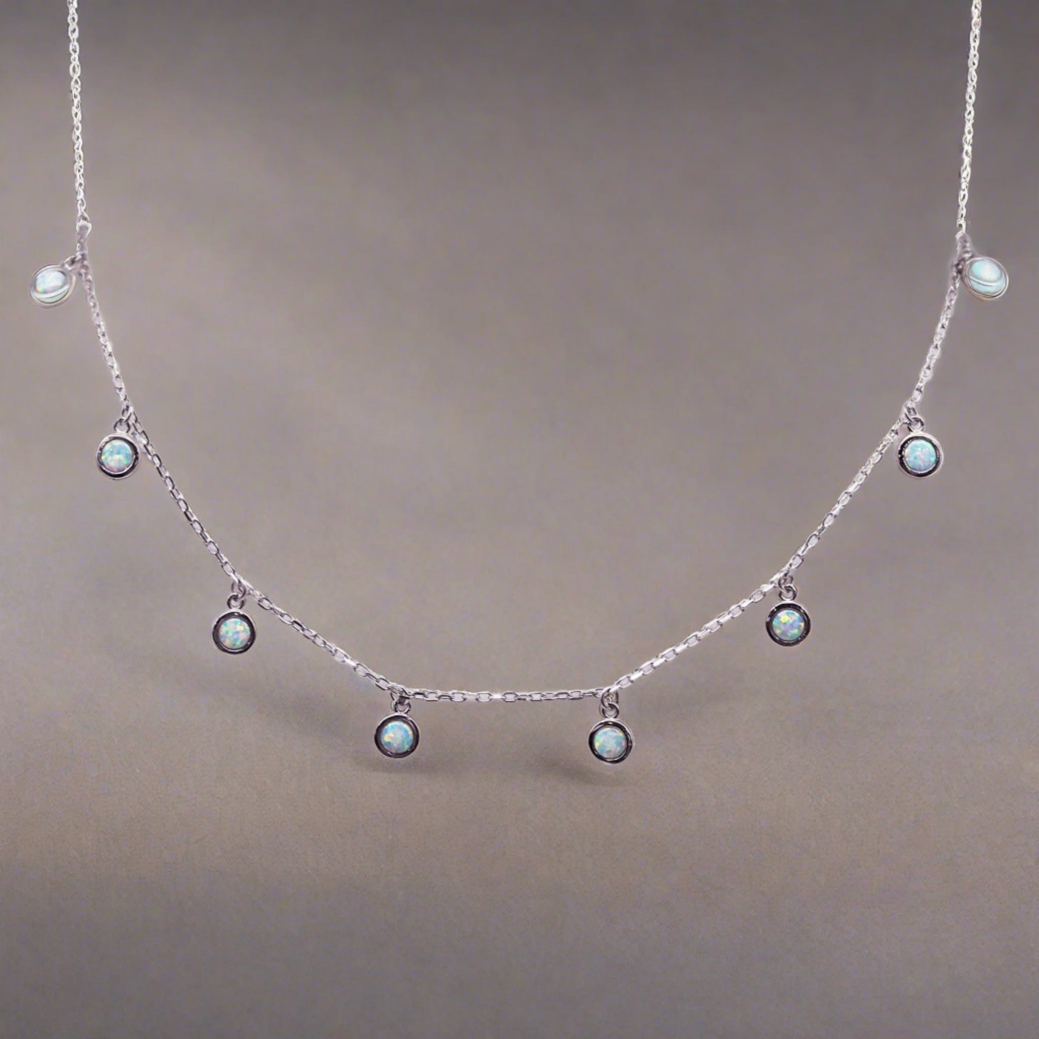 Sterling silver Necklace with small round opal stones on a plain background