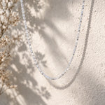 Beaded moonstone necklace on a textured beige surface with dried flowers