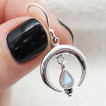 Moonstone sterling silver earring held by fingers against a neutral background