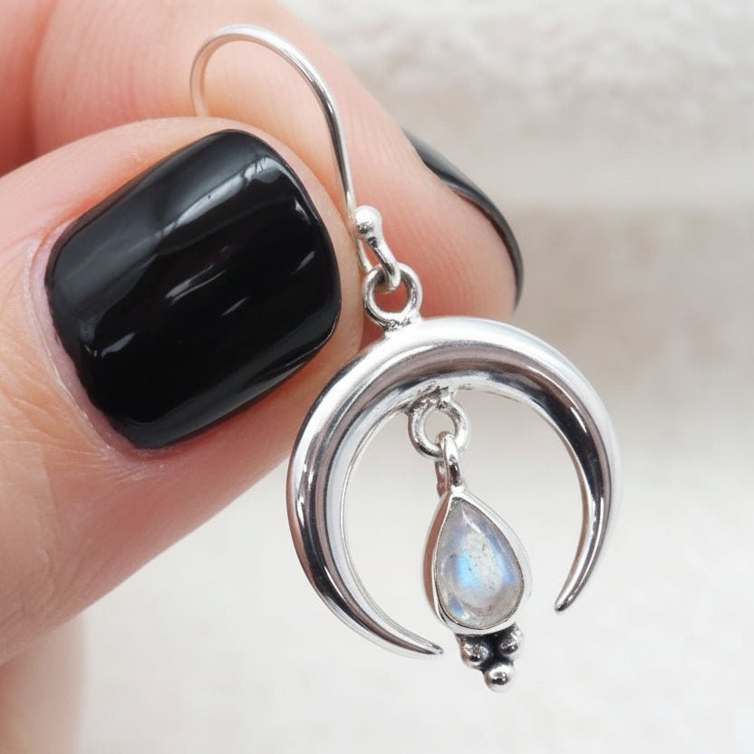 Moonstone sterling silver earring held by fingers against a neutral background