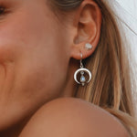 Close-up of a woman wearing a sterling silver half moon earring with a Moonstone.
