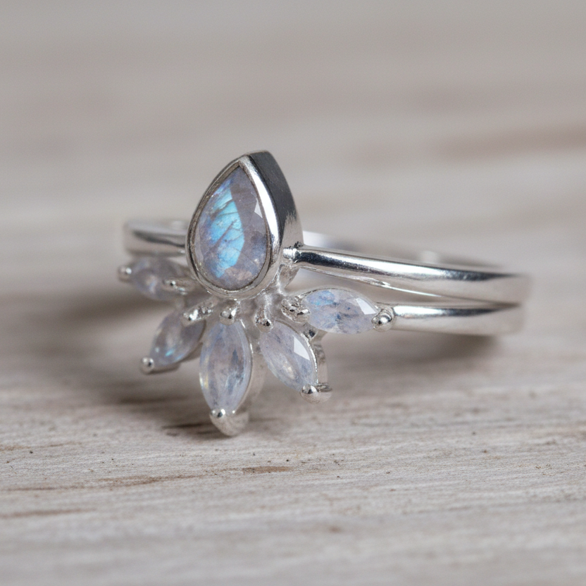 Silver rings with teardrop-shaped moonstones gemstones on a wooden surface