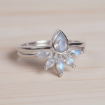Silver rings with teardrop-shaped moonstones gemstone on a light wooden surface