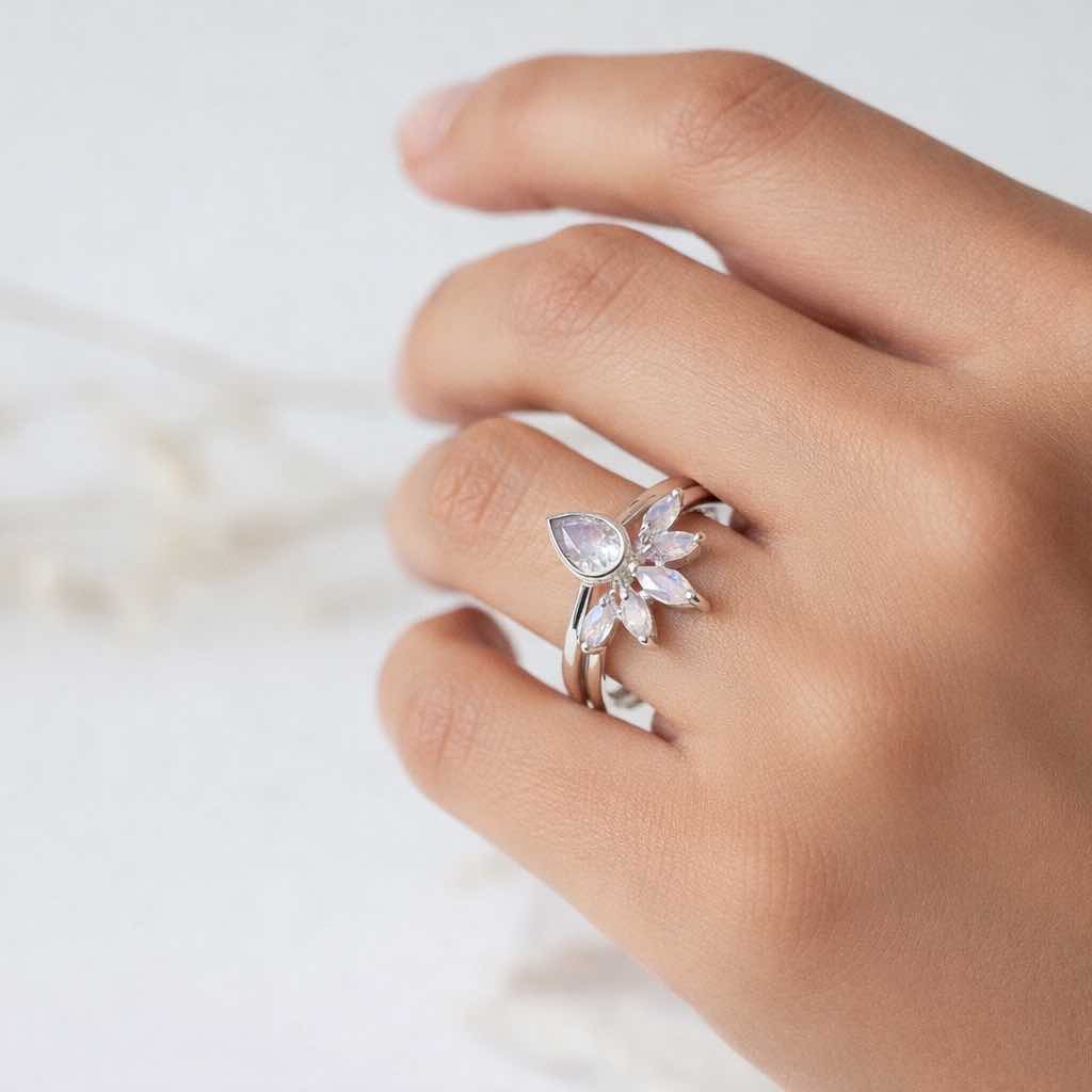 Hand wearing silver rings with moonstones gemstones on a light background