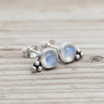 Silver earrings with moonstone stones on a wooden surface