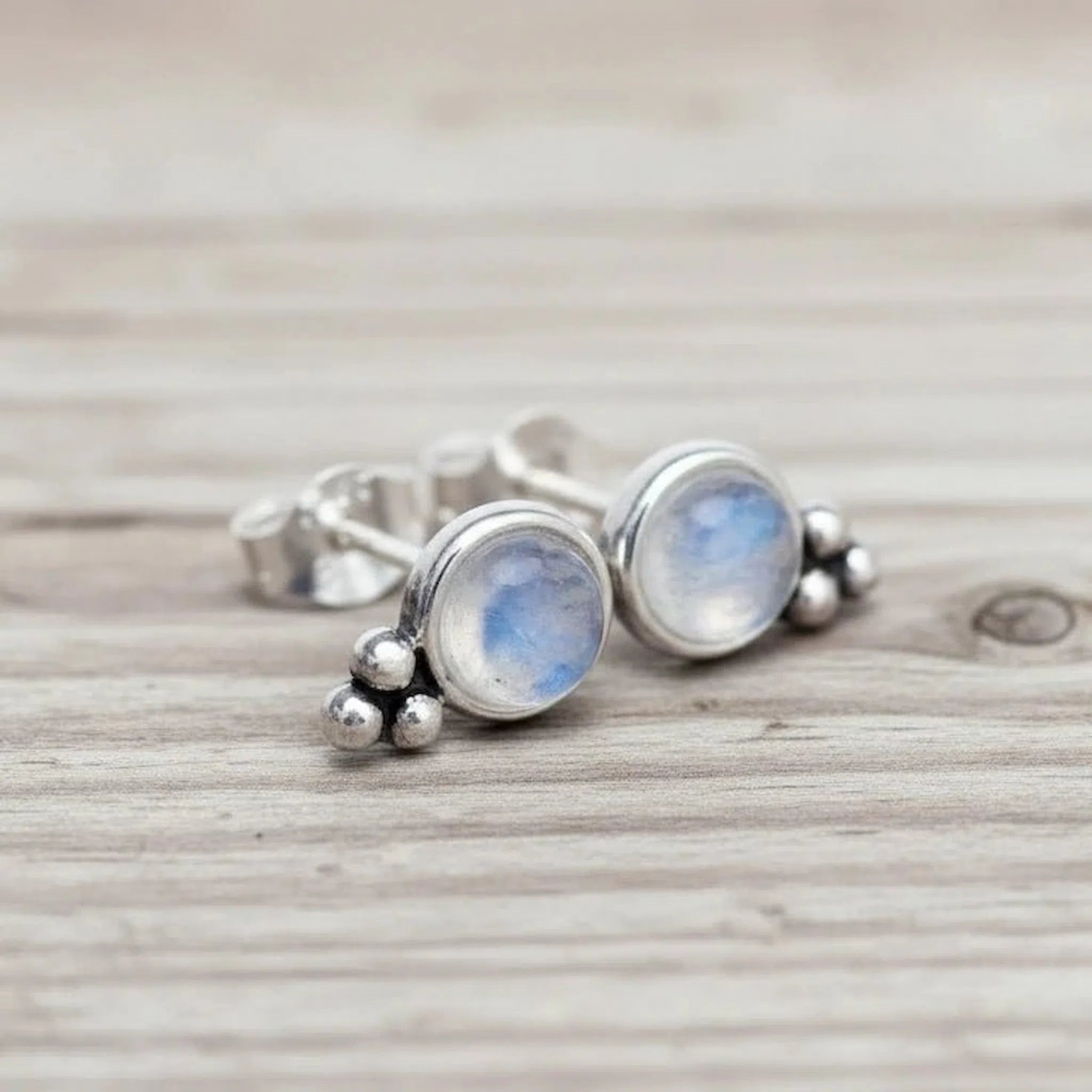 Silver earrings with moonstone stones on a wooden surface