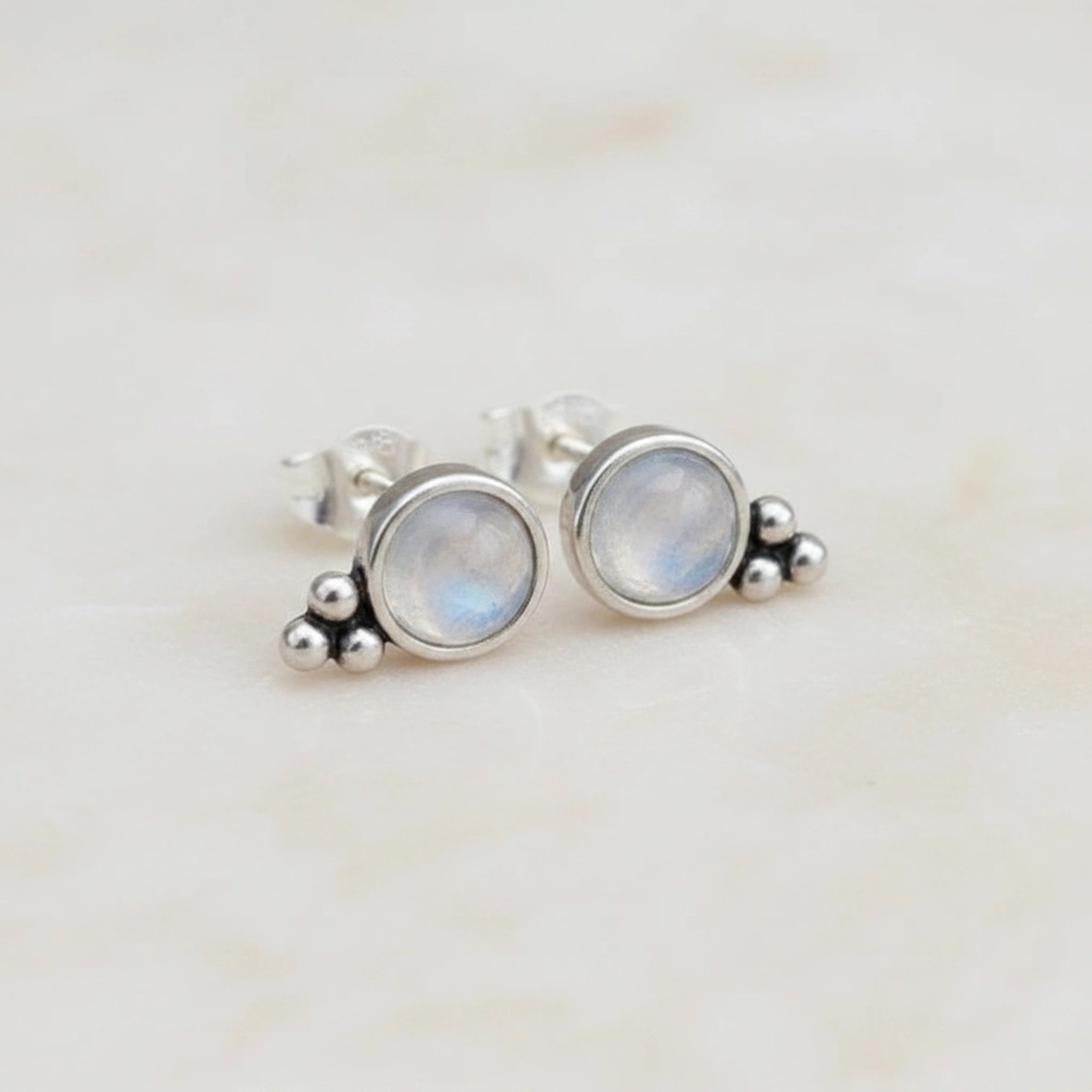 Silver earrings with moonstone stones on a light background