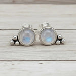Pair of silver earrings with moonstone stones on a wooden surface
