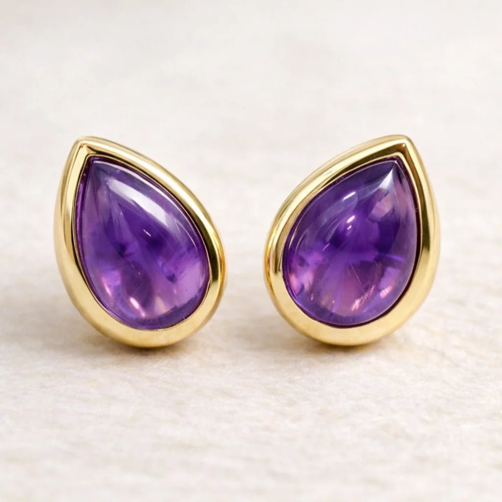 Gold-framed february birthstone teardrop amethyst stud earrings on a light background