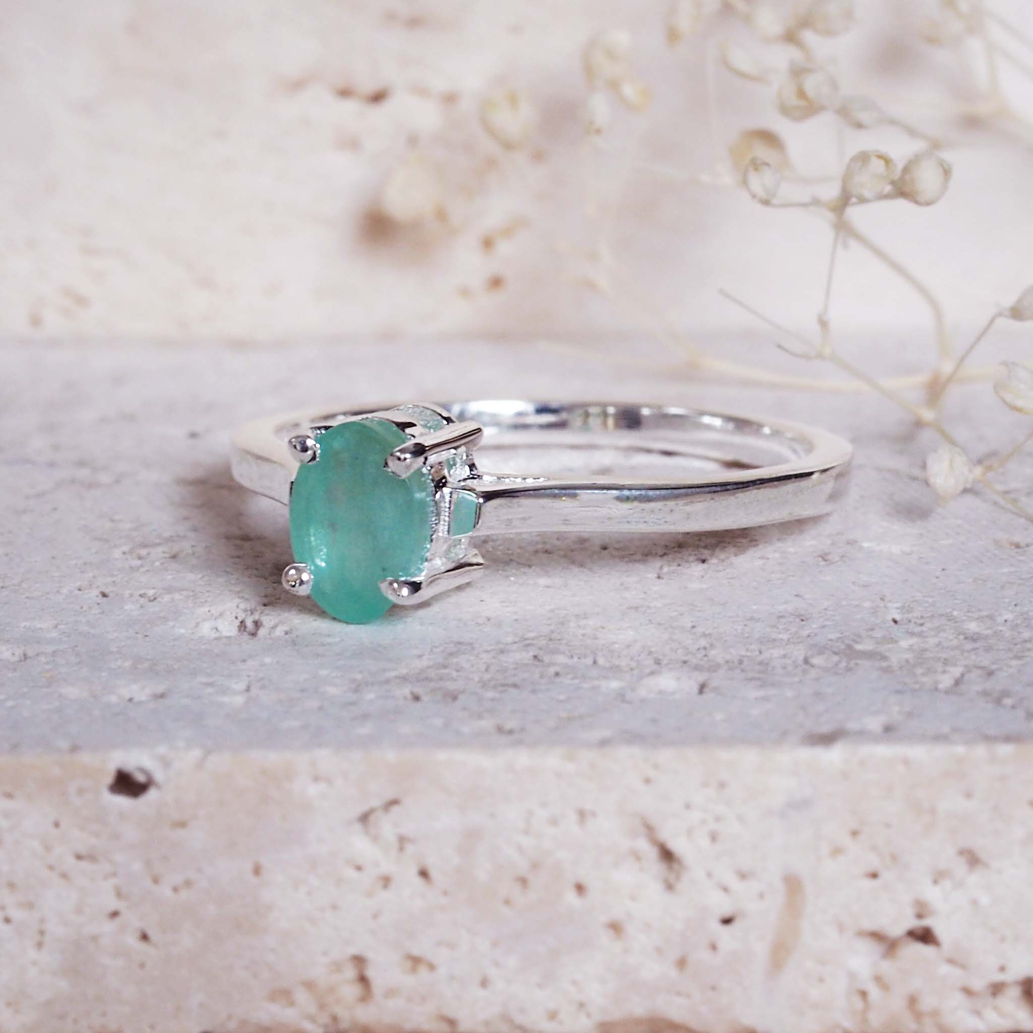 sterling Silver ring with a green emerald gemstone on a textured surface