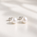 Sterling silver freshwater pearl earrings, a pair of white pearl studs in soft light on cream