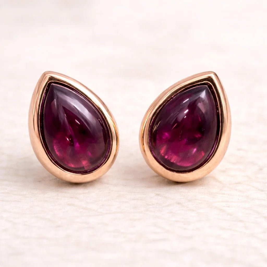 Pair of rose gold january birthstone earrings with teardrop-shaped natural garnet gemstones on a light background