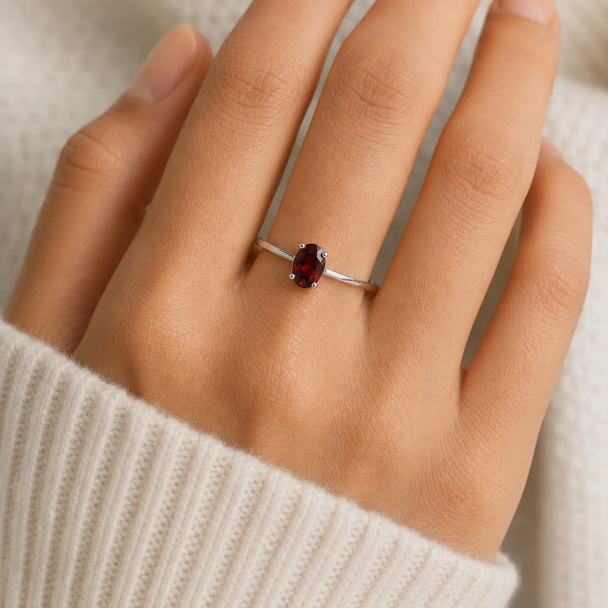 Sterling Silver Claw Set ring with oval faceted natural garnet gemstone on a persons hand.
