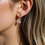 Close-up of an ear wearing a silver earring with a blue topaz gemstone. by indie and harper jewellery australia