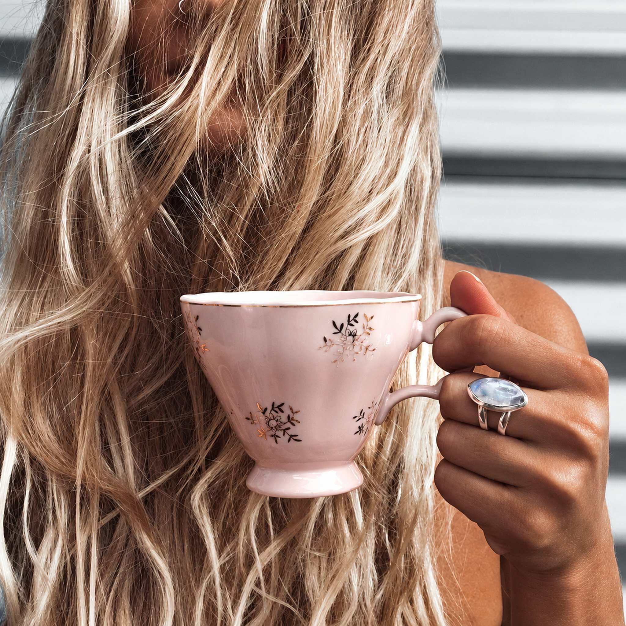 Woman holding a pink tea cup wearing the sterling silver moonstone statement ring