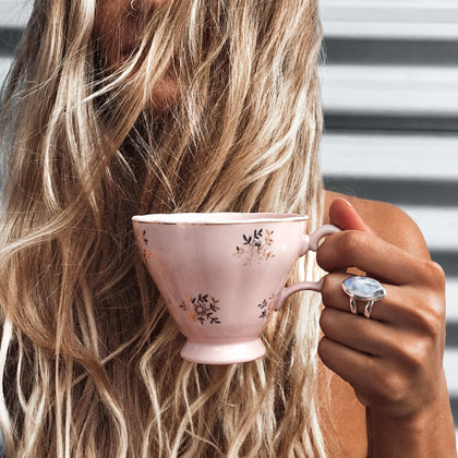 Woman holding a pink tea cup wearing the sterling silver moonstone statement ring