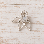 A sterling silver butterfly-shaped stud earring with a central round iridescent moonstone, displayed on a distressed white wooden surface.