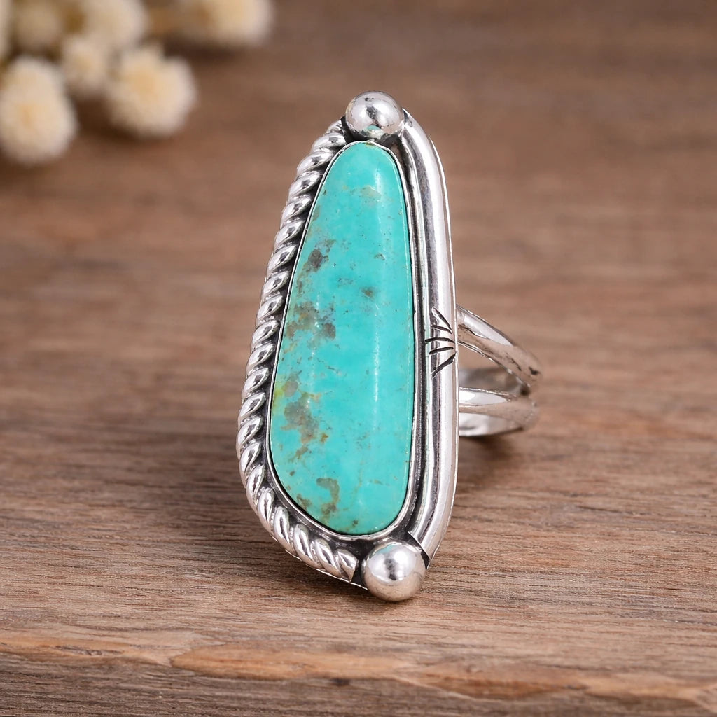 Turquoise ring with silver band on a wooden surface